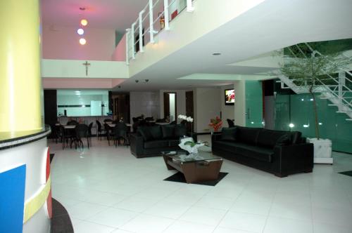 a living room with black couches and a dining room at Hotel Piramide Pituba - Rua Pernambuco in Salvador