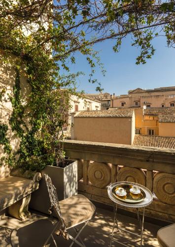 a table and chairs on a balcony with a view at Seven Rooms Villadorata in Noto