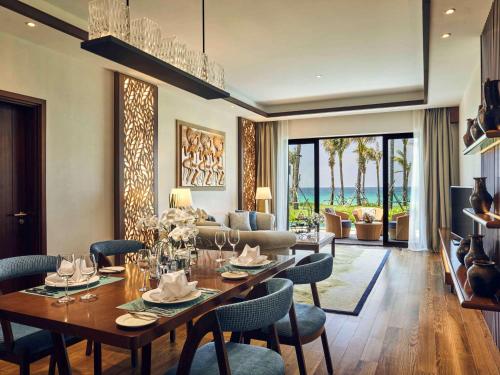 a dining room and living room with a table and chairs at Mövenpick Resort Cam Ranh in Cam Ranh