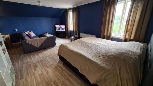 1 dormitorio con paredes azules, 1 cama y 1 sofá en Own apartment in village school from 1886 with private entrance en Kristianstad