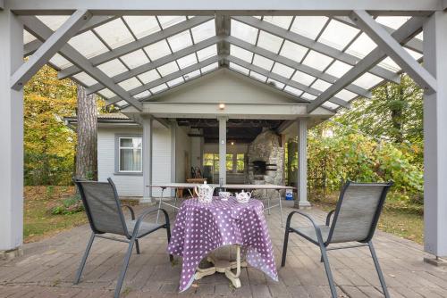 a table and chairs on a patio with a pergola at Valensija in Jūrmala
