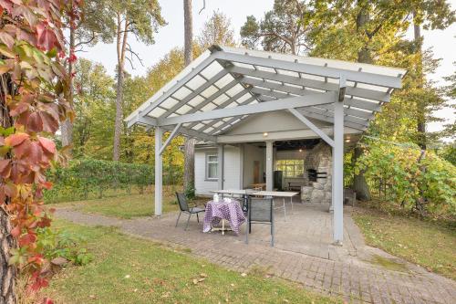 a white pergola with a table and chairs at Valensija in Jūrmala