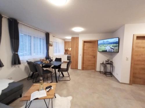 a living room with a table and a tv on the wall at The AlpenHouse Gligic´s in Sautens