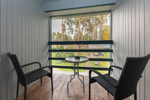 a porch with two chairs and a table and a window at Valensija in Jūrmala