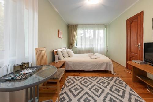 a room with a bed and a table and a television at Valensija in Jūrmala