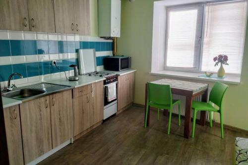 a kitchen with green chairs and a table and a kitchen with a sink at Family and friends apartment in Ternopilʼ