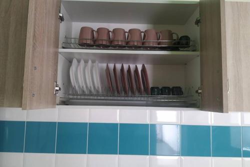 a cupboard with plates andugs on it in a kitchen at Family and friends apartment in Ternopilʼ