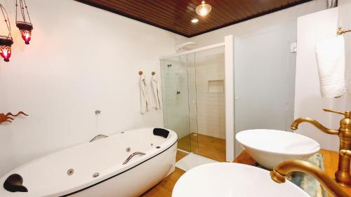 a white bathroom with a tub and a sink at Pousada Pura Vida Maresias in Maresias