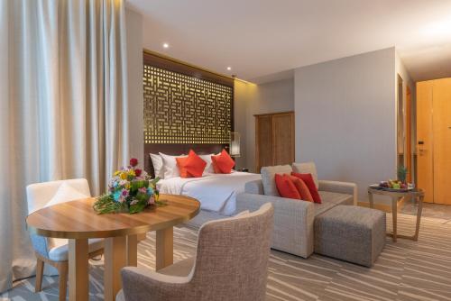 a hotel room with a bed and a table and chairs at Ramada Hotel & Suites by Wyndham Al Qassim in Al Bukayriyah