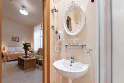 a bathroom with a sink and a mirror and a bed at Valensija in Jūrmala