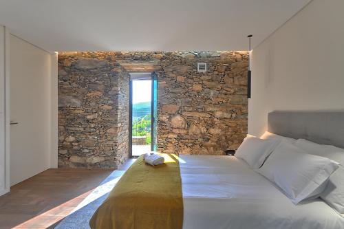 1 dormitorio con 1 cama con pared de piedra en DouroXisto, en Peso da Régua