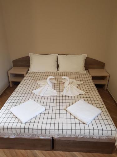 a bed with white sheets and towels on it at Хотелски комплекс САНЯ in Apriltsi