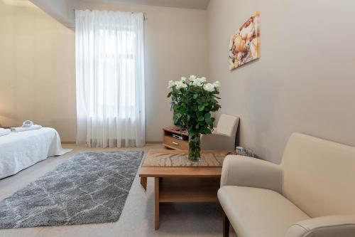 a living room with a table with a vase of flowers at Valensija in Jūrmala