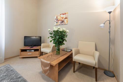a living room with a table and two chairs and a television at Valensija in Jūrmala