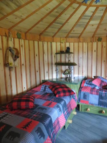 Habitación con 2 camas en una cabaña de madera en La Maison sous les arbres, en Saint Roch de Mekinac