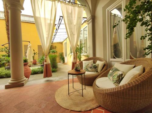 - une terrasse couverte avec des chaises en osier et une table dans l'établissement Ricasoli Garden Relais, à Florence