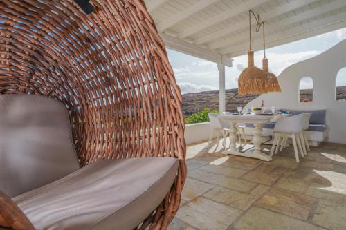 a wicker swing chair in a patio with a table at VLIA MAR Myconian Residences in Kalafatis