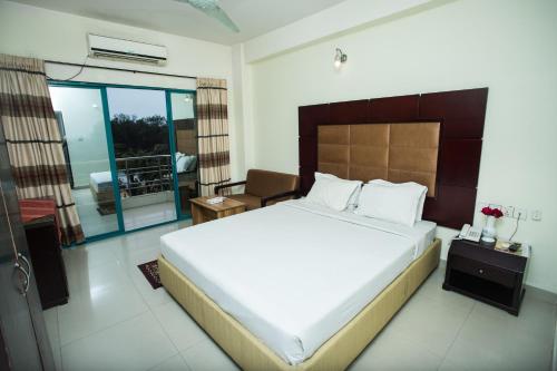 1 dormitorio con 1 cama grande y balcón en Hotel Mishuk, en Cox's Bazar