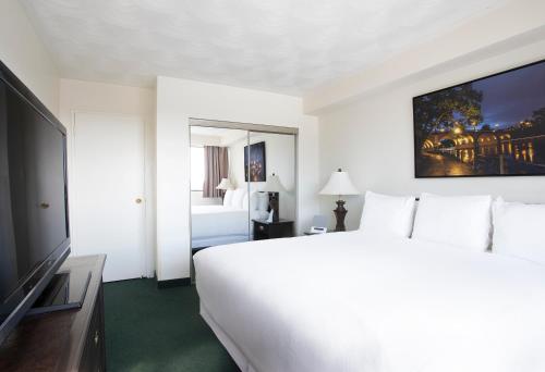 a hotel room with a large white bed and a television at The Business Inn in Ottawa