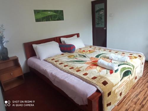 Una cama con edredón en un dormitorio en Lassana Villa, en Nuwara Eliya