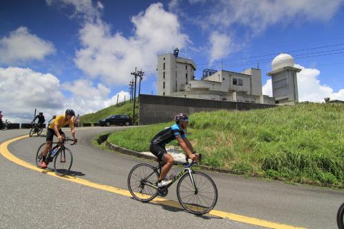 two men riding bikes down a road with a castle in the background at 106 Homestay in Ruifang