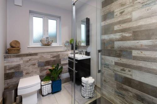 uma casa de banho com uma parede de madeira, um WC e um lavatório. em Roseland Apartment 4 em Arundel