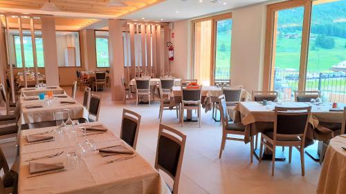 a dining room with tables and chairs and windows at Livì Family Hotel in Livigno