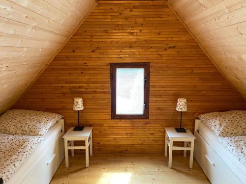 two beds in a wooden room with a window at Chata Petrofka in Zdislava