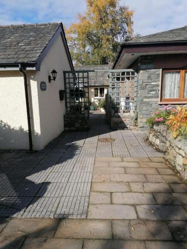 a house with a brick walkway next to a building at Lakeland Snug in Keswick