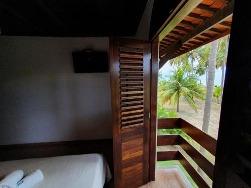 a room with a bed and a view of the beach at Pousada Igrejinha dos Carneiros in Tamandaré