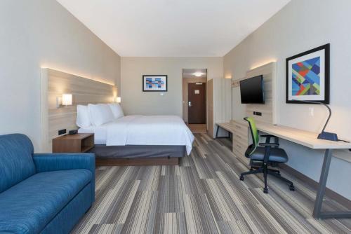 a hotel room with a bed and a desk and a couch at Holiday Inn Express & Suites - Grand Rapids Airport - South by IHG in Grand Rapids