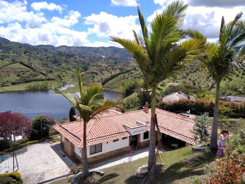 CASA CAMPESTRE MONTECARLO Guatapé- desayuno a pareja في غواتابيه: منزل فيه نخل امام بحيرة