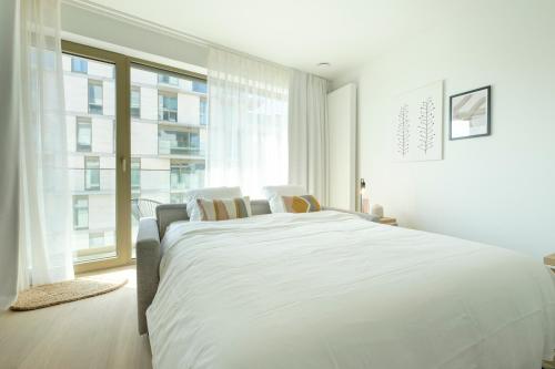 a white bedroom with a large bed and a window at The Riverside in Brussels