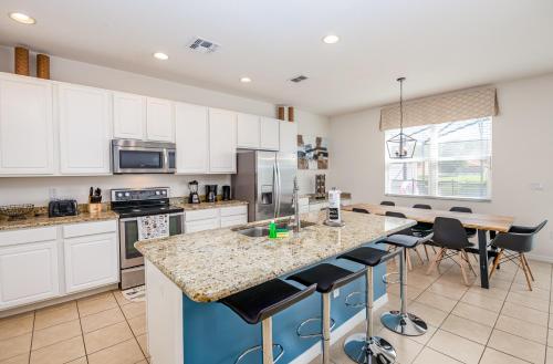 una cocina con armarios blancos y una isla con taburetes. en Fantastic Lakeview Townhome near Disney en Kissimmee
