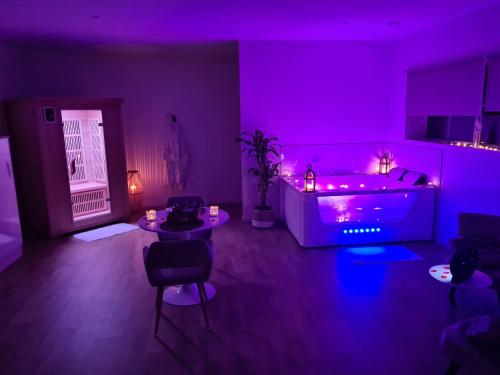 Cette chambre violette comprend un lit, une table et des chaises. dans l'établissement L escapade amoureuse, à Bournezeau