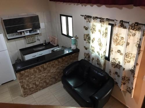 a kitchen with a black leather chair in a room at Apartamento no Centro de Mongaguá in Mongaguá
