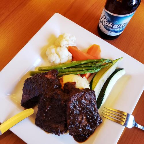 a plate of food with meat and vegetables and a drink at James Bay Inn Hotel, Suites & Cottage in Victoria