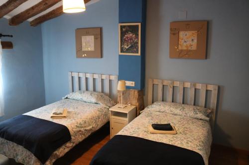 2 camas en un dormitorio con paredes azules en Casa rural tres regiones en Ontiñena