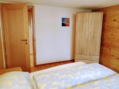 een slaapkamer met een bed en een houten kast bij Chalet Adler in Grächen
