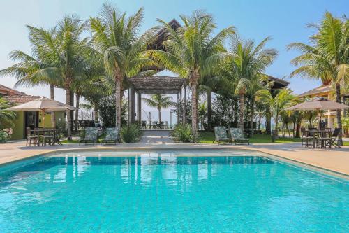 a large swimming pool with palm trees and chairs at Estaleiro Guest House in Balneário Camboriú