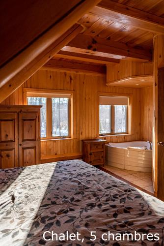 a bedroom with a large bed and two windows at Chalets et Spa Lac Saint-Jean in Chambord