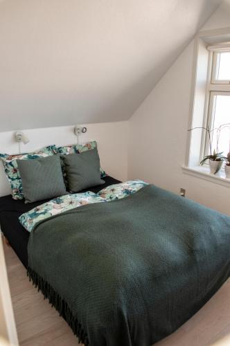 a bedroom with a large bed with a green blanket at Samsø Perlen in Sælvig