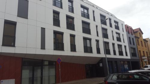 a white building with black windows and a parking lot at Apartament Skarbowa 1 in Leszno