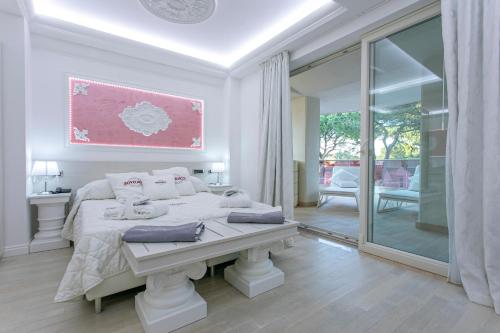 a white bedroom with a bed and a large mirror at Boutique Hotel Paradiso in Milano Marittima