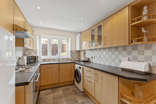 a kitchen with wooden cabinets and a washer and dryer at The Pink House, Paignton in Paignton
