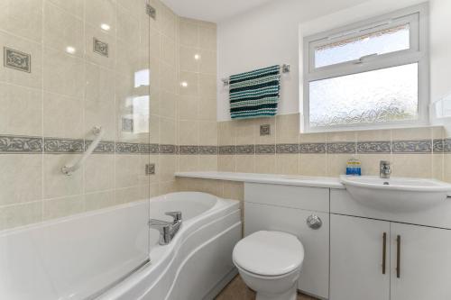 a bathroom with a tub and a toilet and a sink at The Pink House, Paignton in Paignton