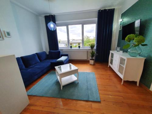 a living room with a blue couch and a table at Apartamenty pod Wieżą in Zgorzelec
