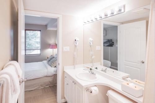 a bathroom with a sink and a mirror and a bed at Deer Lodge by Outpost Whistler in Whistler