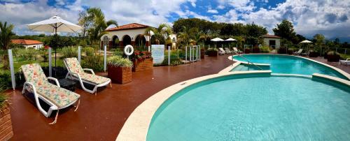 a large swimming pool with chairs and an umbrella at Hotel Estrella Del Monte in Armenia