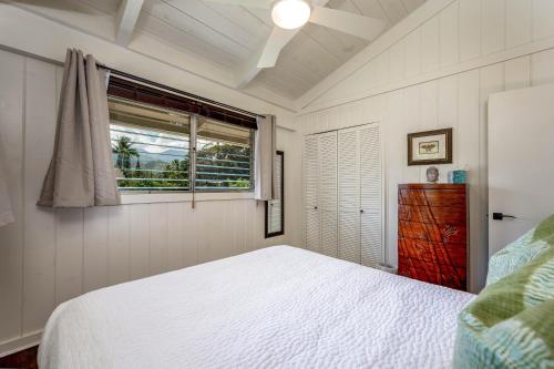 a bedroom with a white bed and a window at Hale Naninoa home in Hanalei